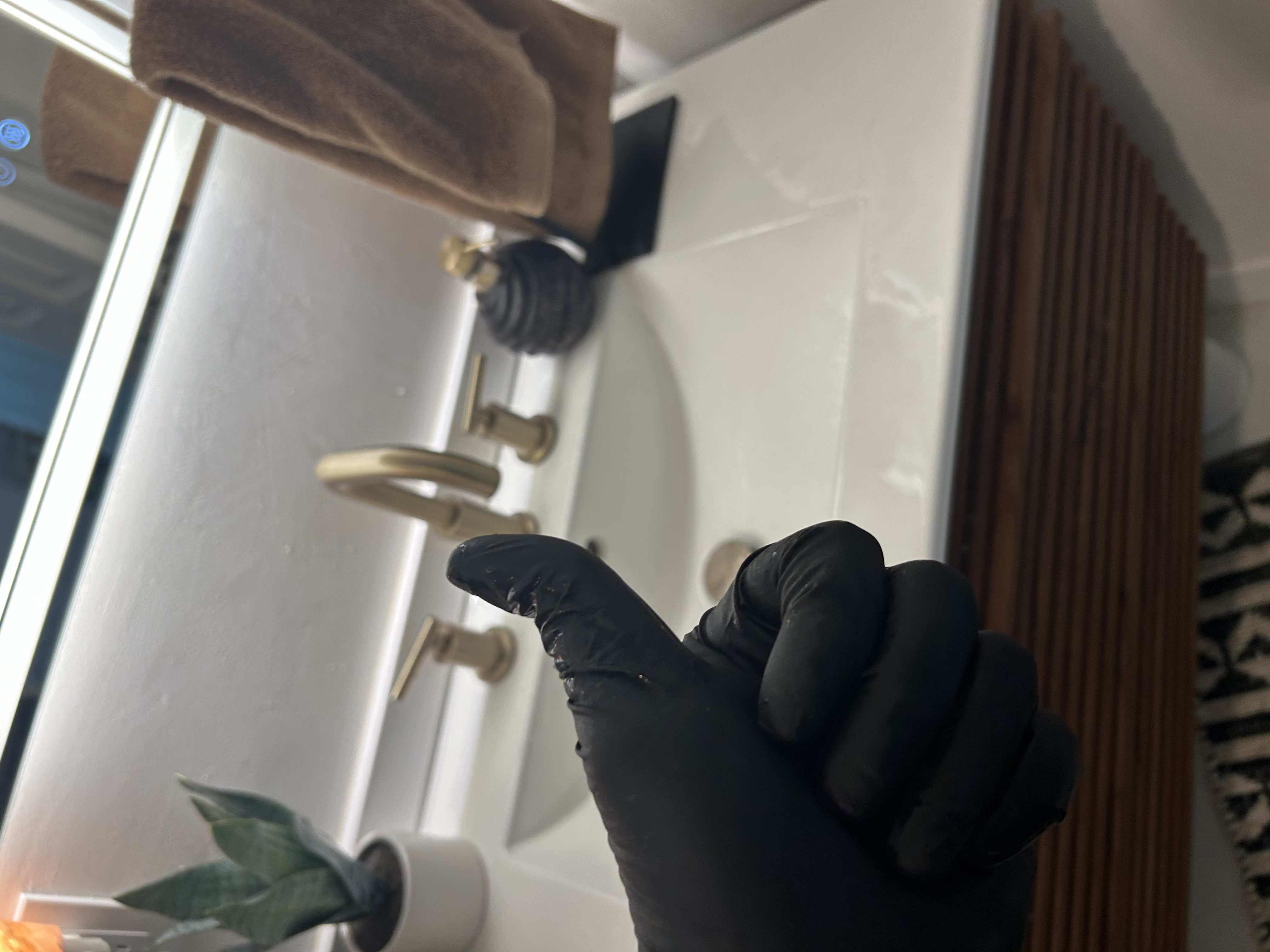 Matt's gloved hand holding debris removed from sink pop-up assembly — Scottsdale rental guest bath — Desert Rain Plumbing