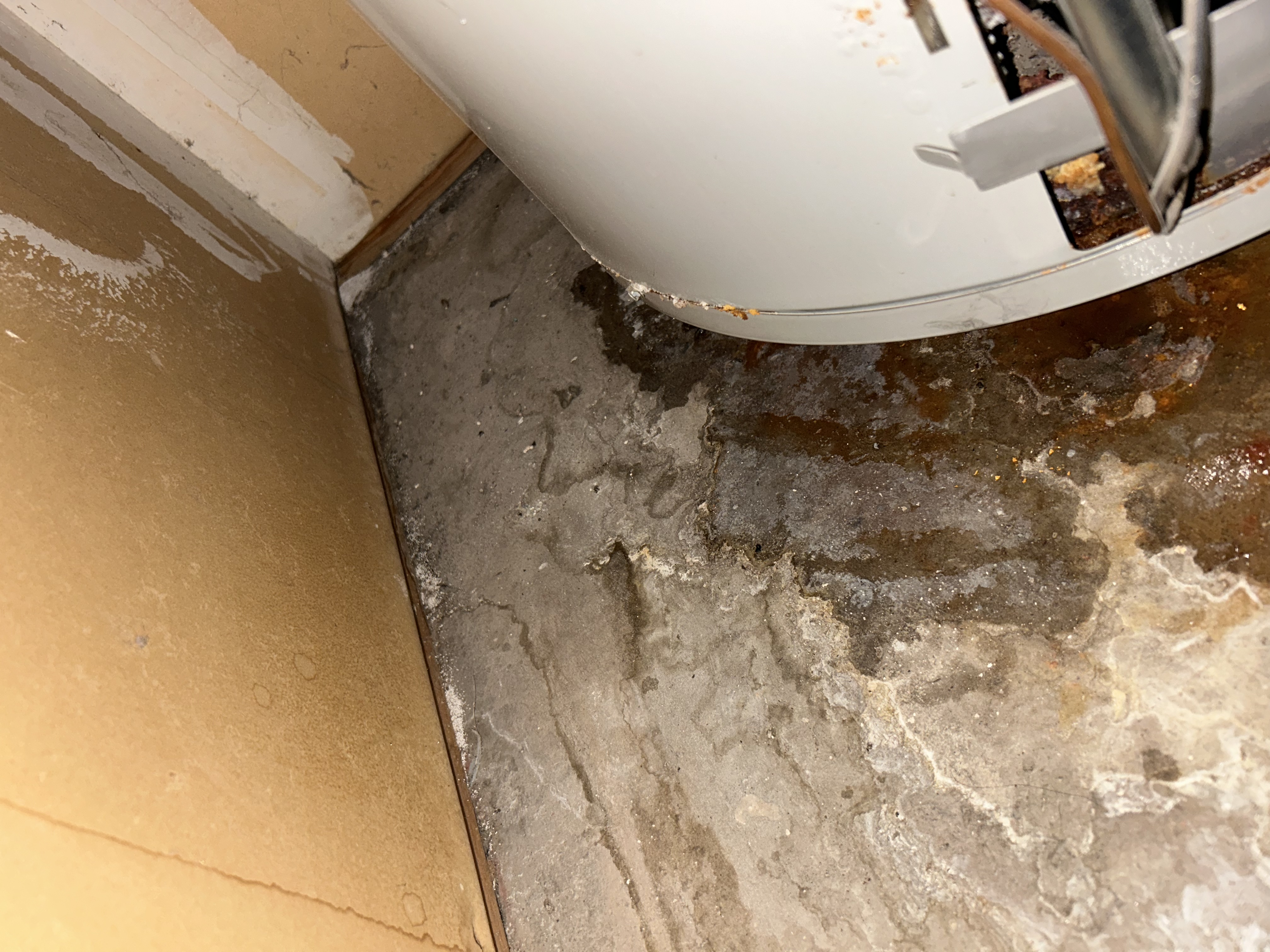 Water damage and mineral deposits on floor from leaking water heater