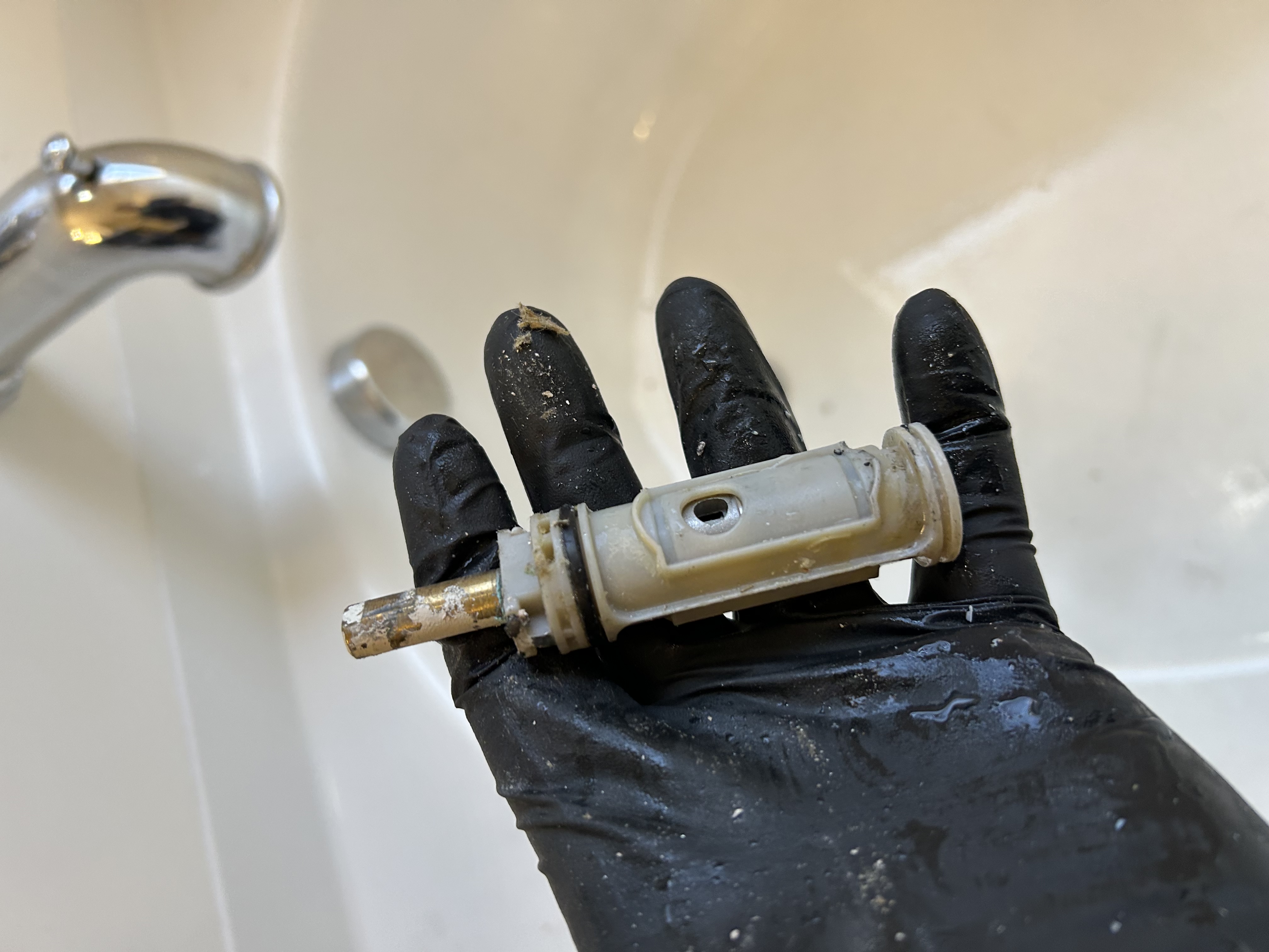 Pulled Moen Positemp cartridge held after removal — corrosion and mineral deposits visible — Desert Rain Plumbing