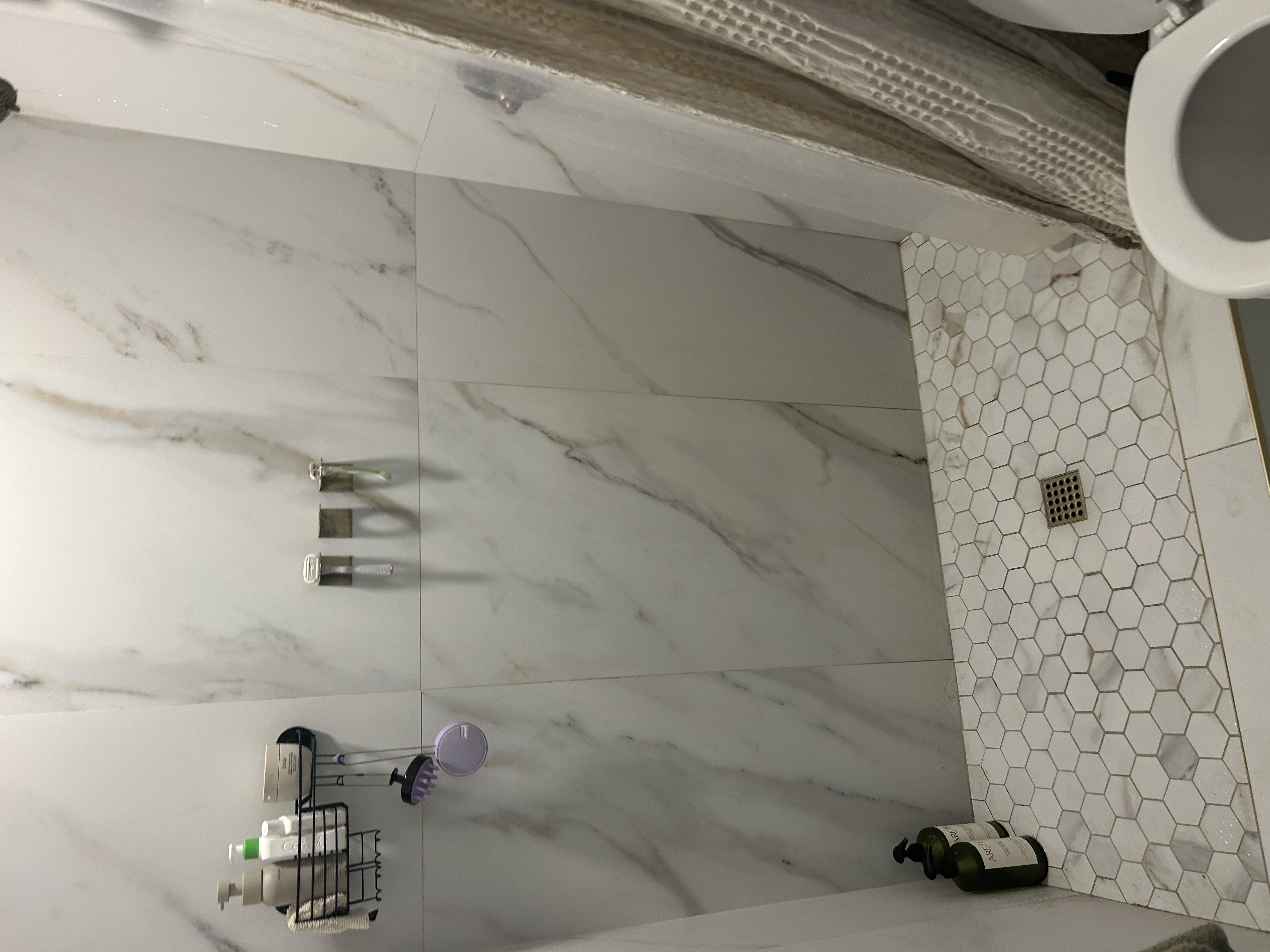 Guest bath standup shower with hexagonal tile floor and brushed-gold square drain plate — Scottsdale AZ rental property before drain clearing