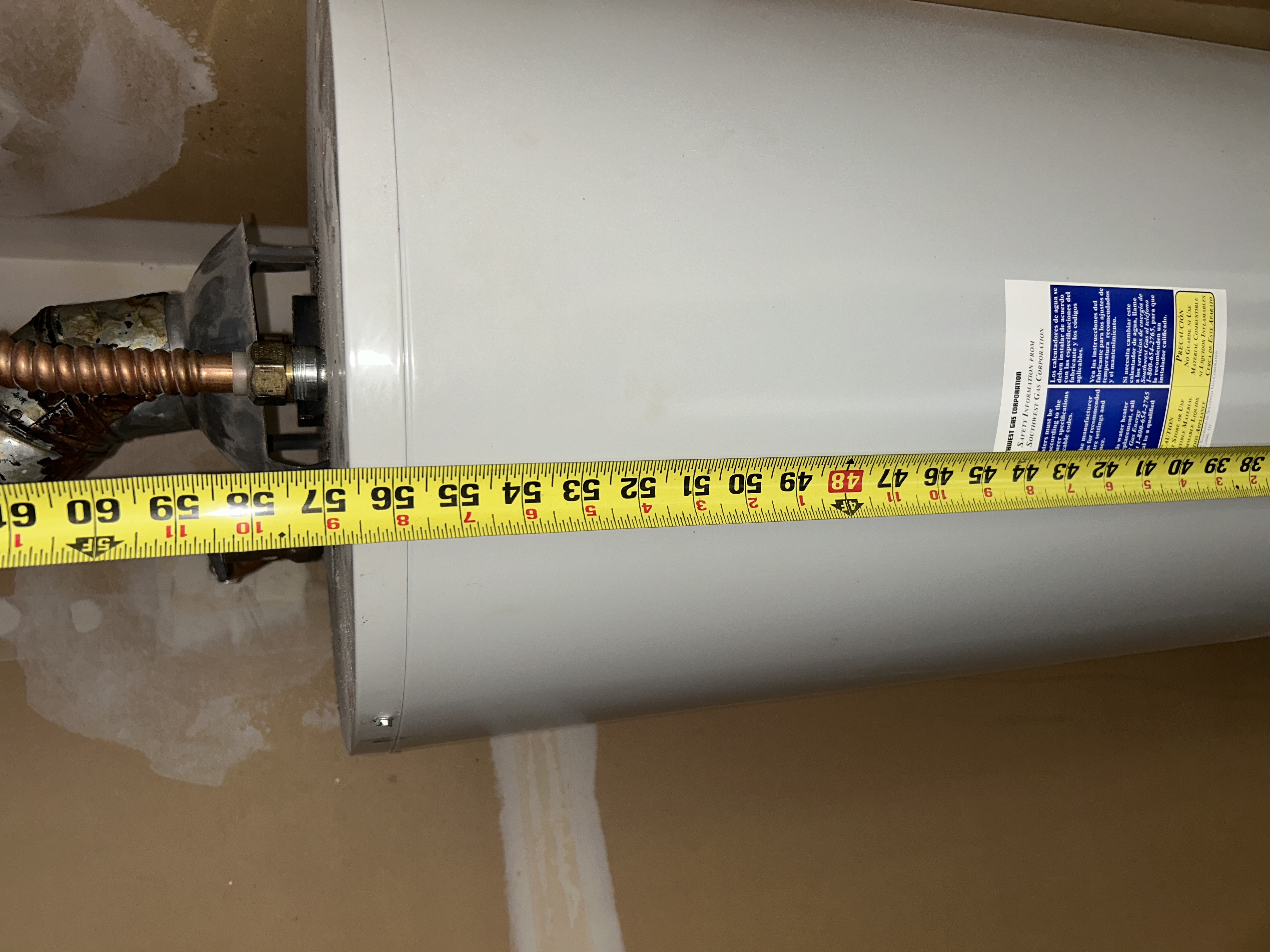 Plumber measuring old water heater diameter for replacement sizing